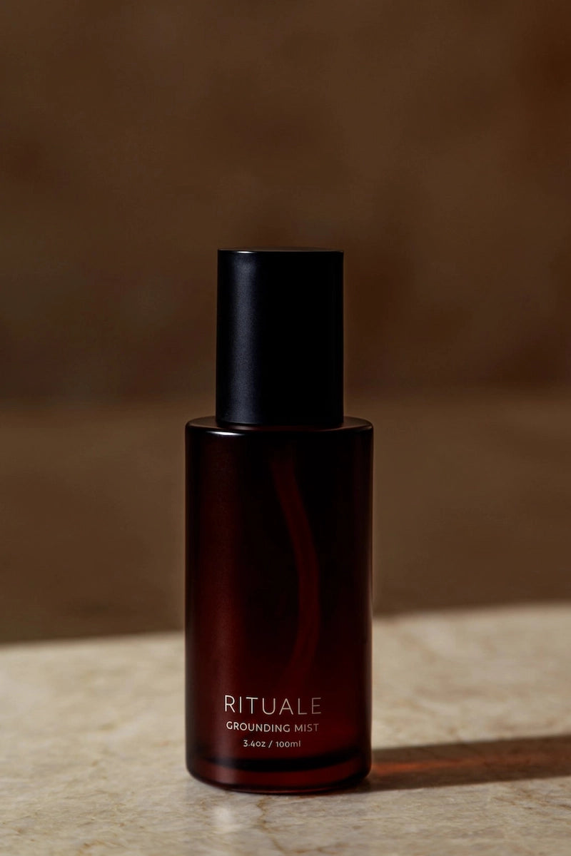 Rituale Grounding Mist 100ml amber glass bottle on marble surface with dark background
