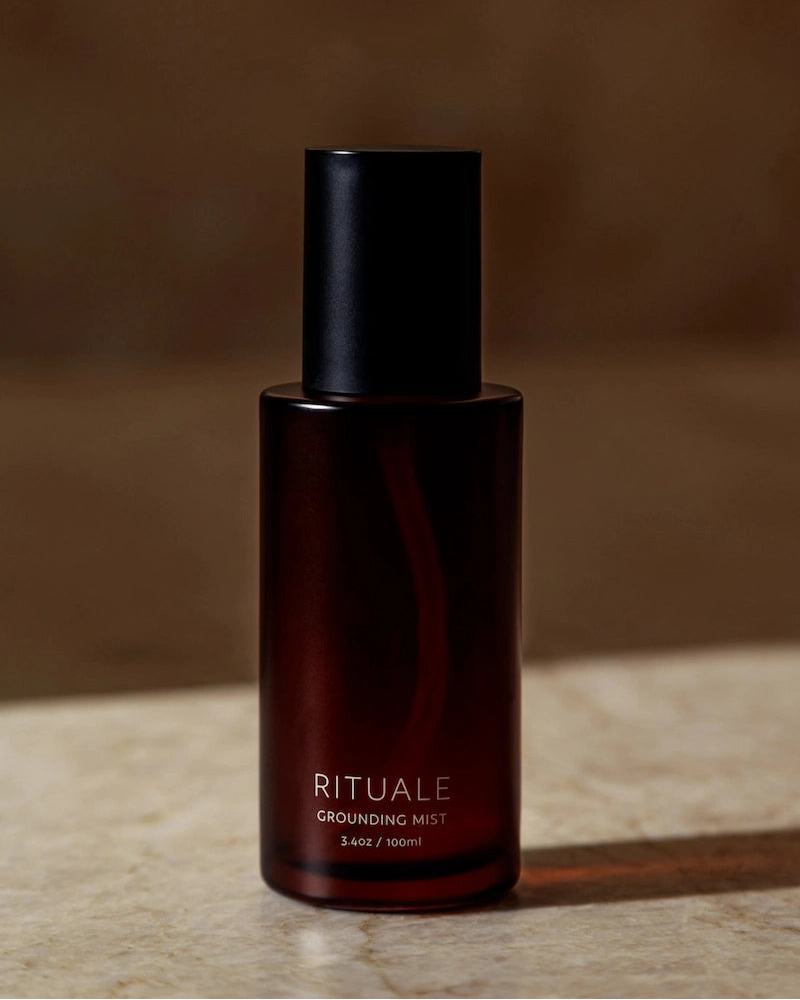 Rituale Grounding Mist 100ml amber glass bottle on marble surface with dark background