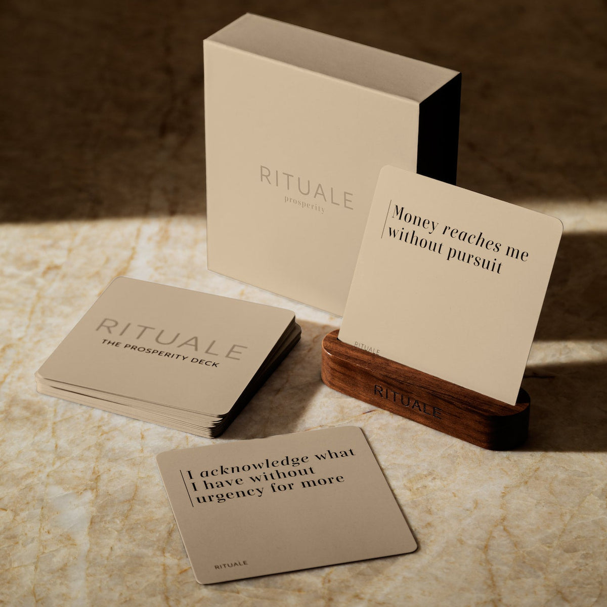 The Prosperity Deck affirmation
cards, box, and walnut display
stand on marble.