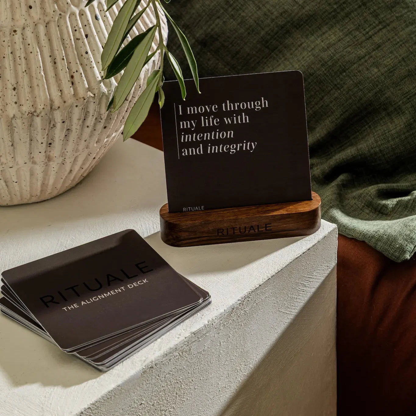Rituale Alignment Deck and card stand on bedside surface with olive branch and ceramic vase