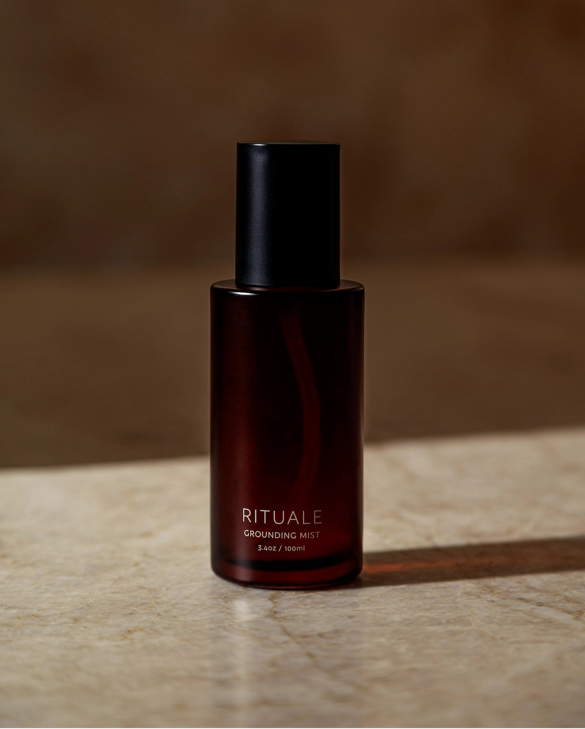 Rituale Grounding Mist 100ml amber glass bottle on marble surface with dark background