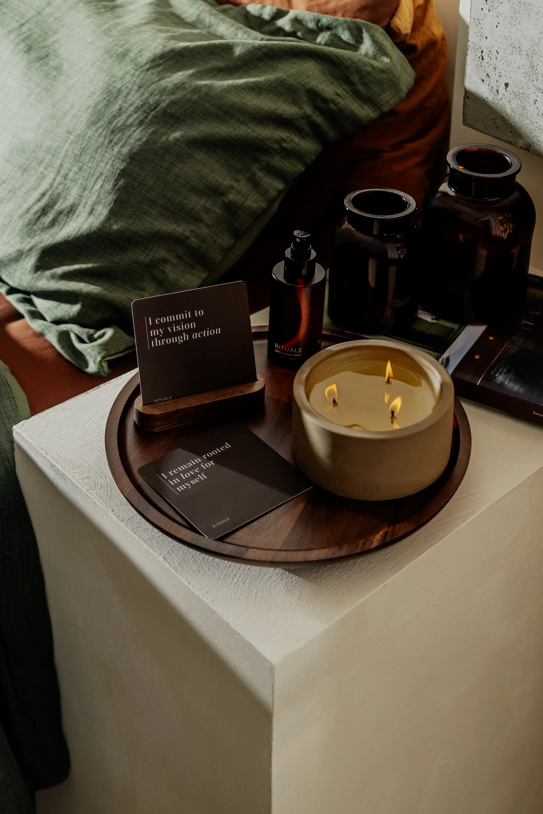 Rituale collection arranged on nightstand tray with lit candle, grounding mist and alignment deck cards