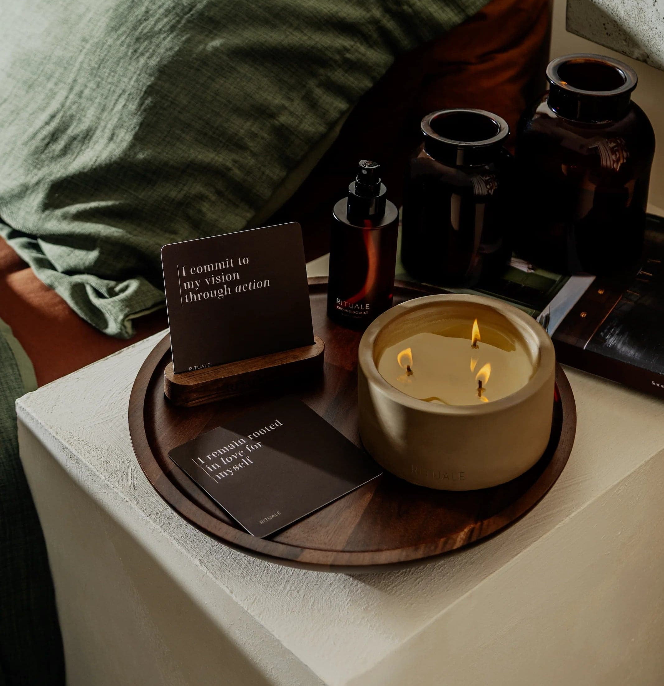 Rituale collection arranged on nightstand tray with lit candle, grounding mist and alignment deck cards