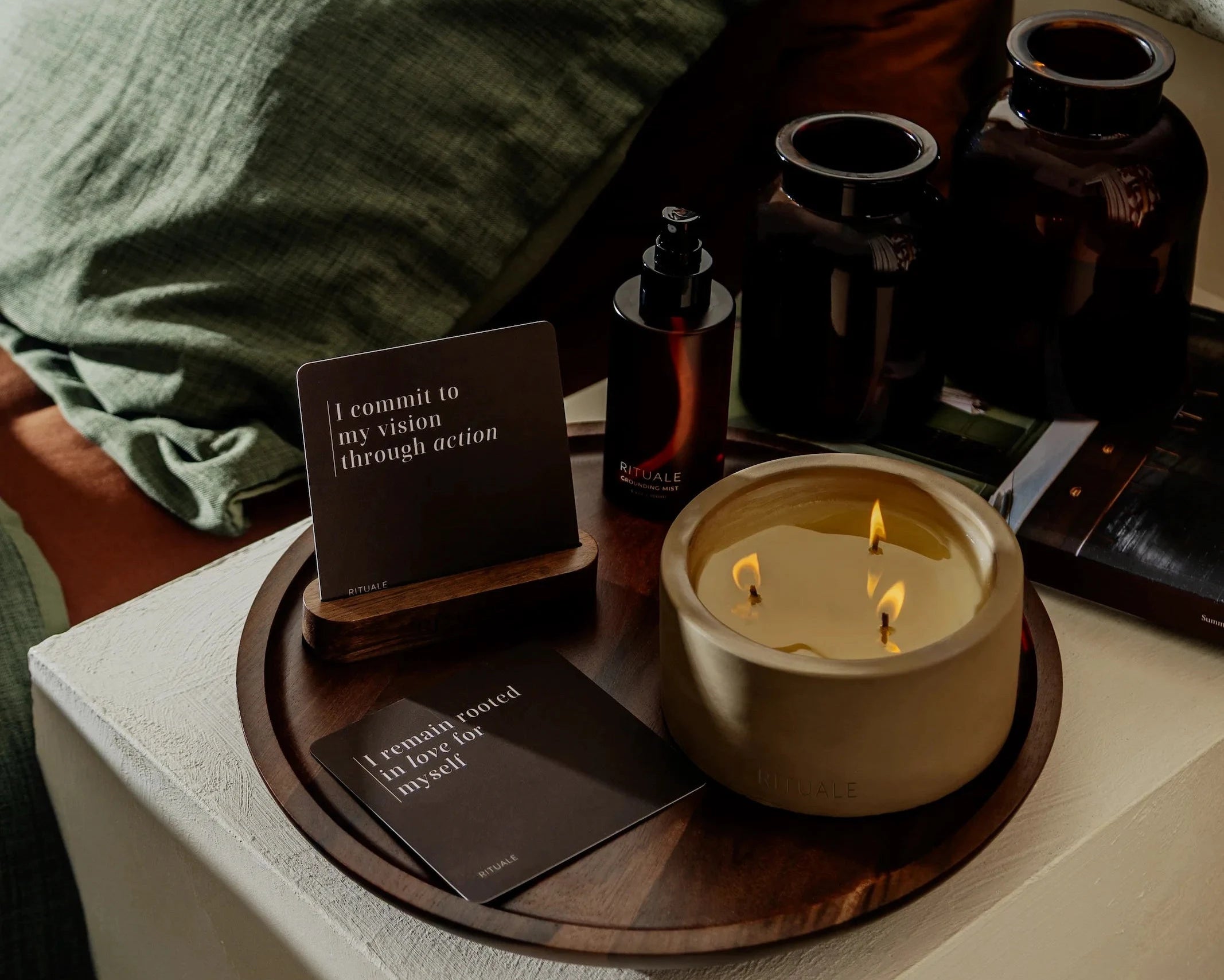Rituale collection arranged on nightstand tray with lit candle, grounding mist and alignment deck cards
