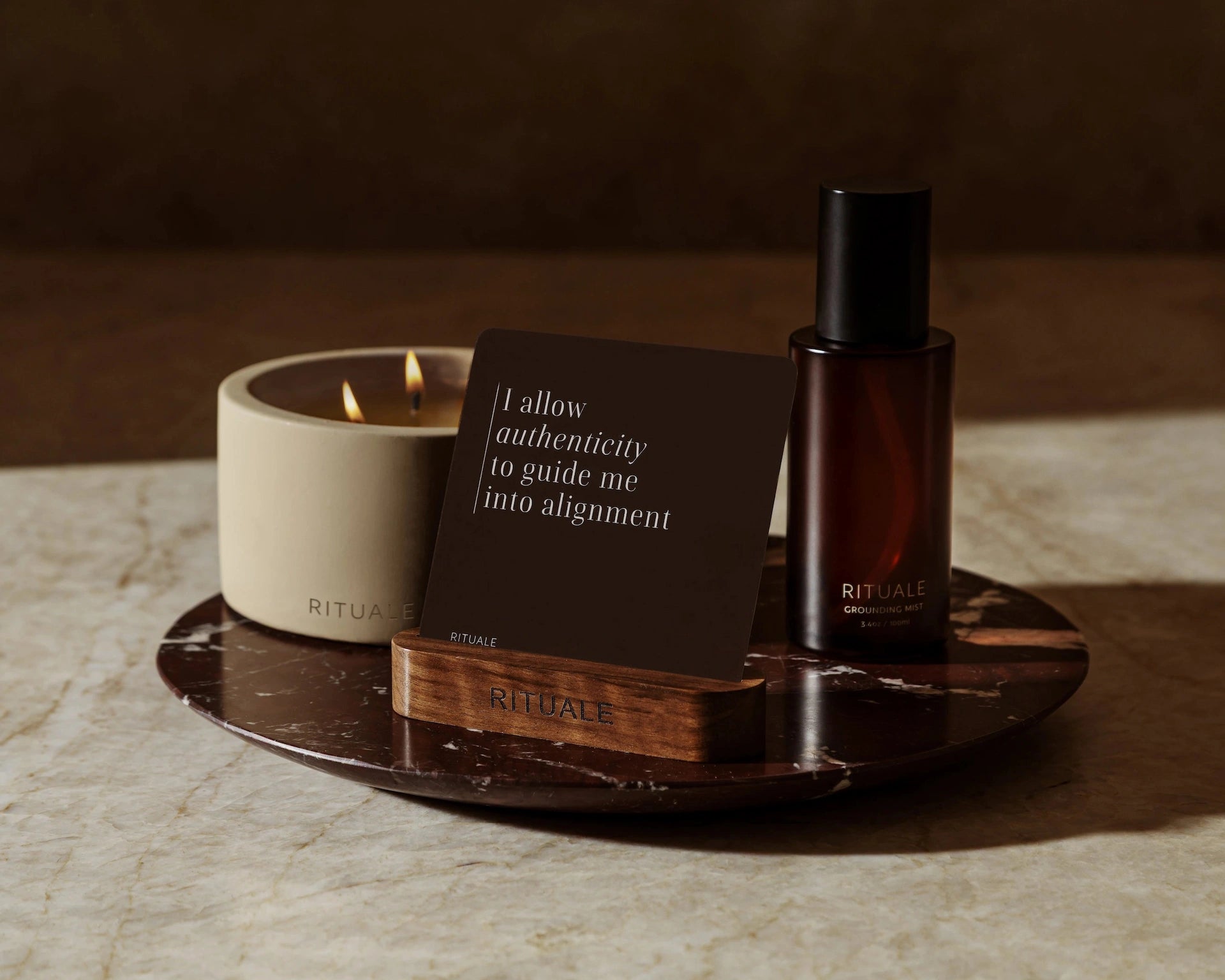 Rituale candle, grounding mist and alignment deck arranged on dark marble tray
